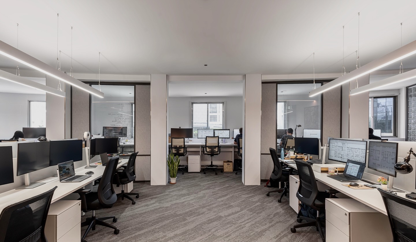 Grey Image of an office with multiple desk and chair.